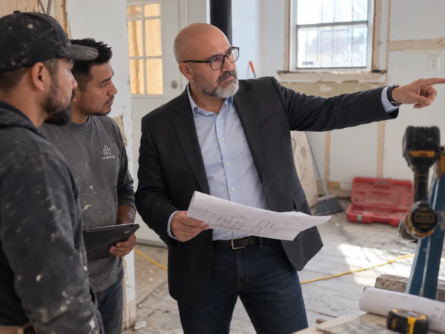 Patrick Iturra reviewing renovation plans with contractors during a real estate asset oversight visit in Los Angeles.